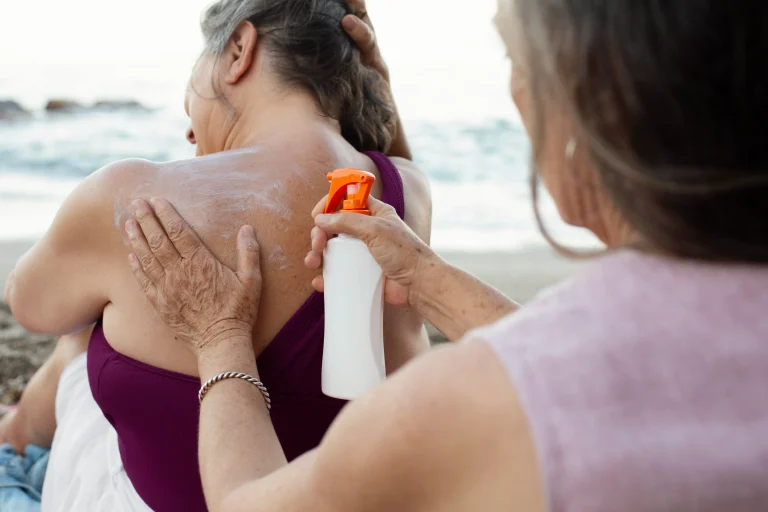 senior-women-applying-sunscreen-back-beach