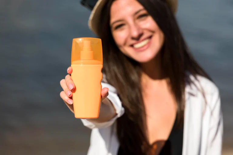 smiley-woman-holding-bottle-sunscreen-beach